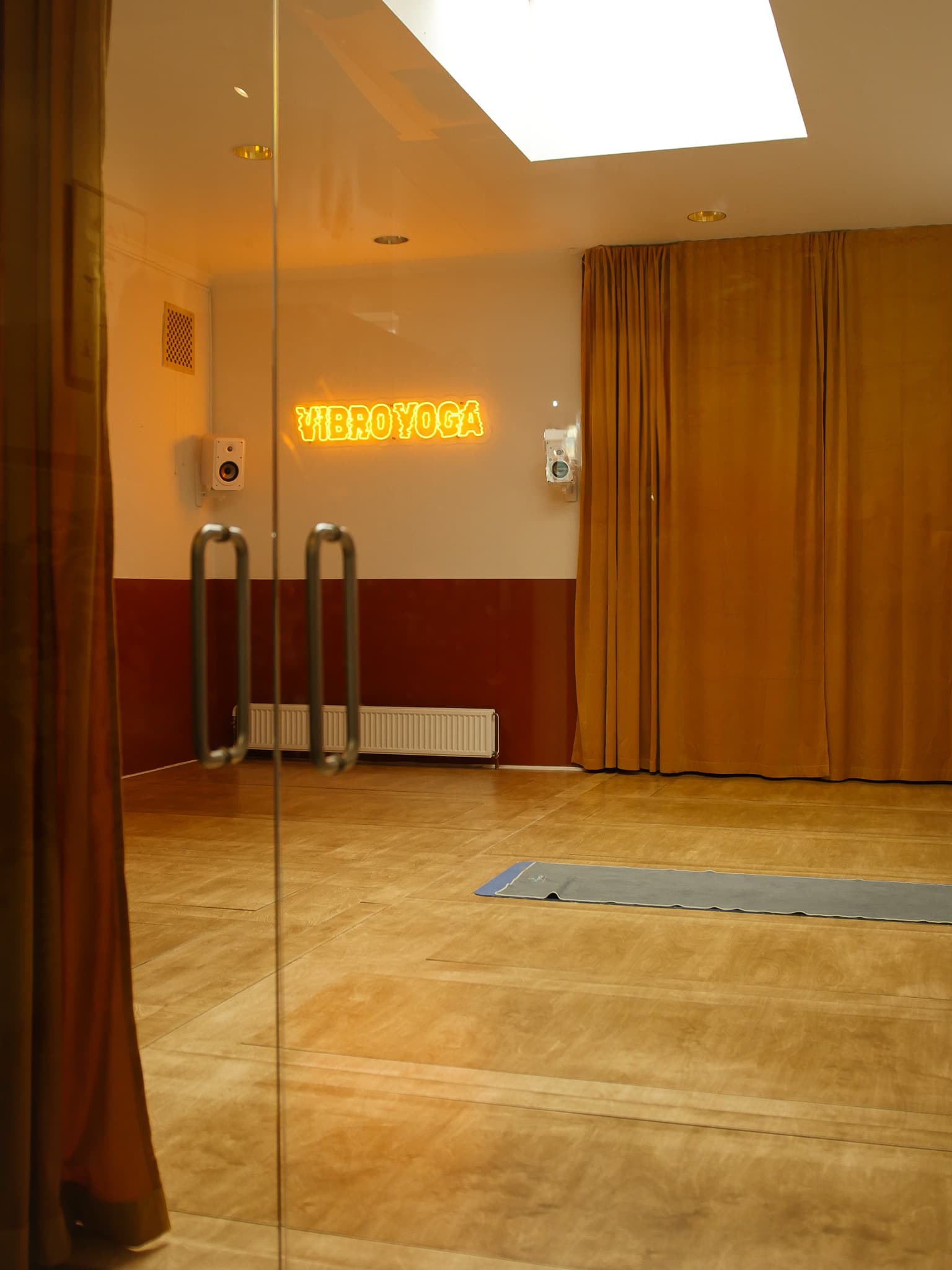 Vibro Yoga-studiet — et varmt vibroakustisk trægulv under det lysende VIBRO YOGA-neonskilt